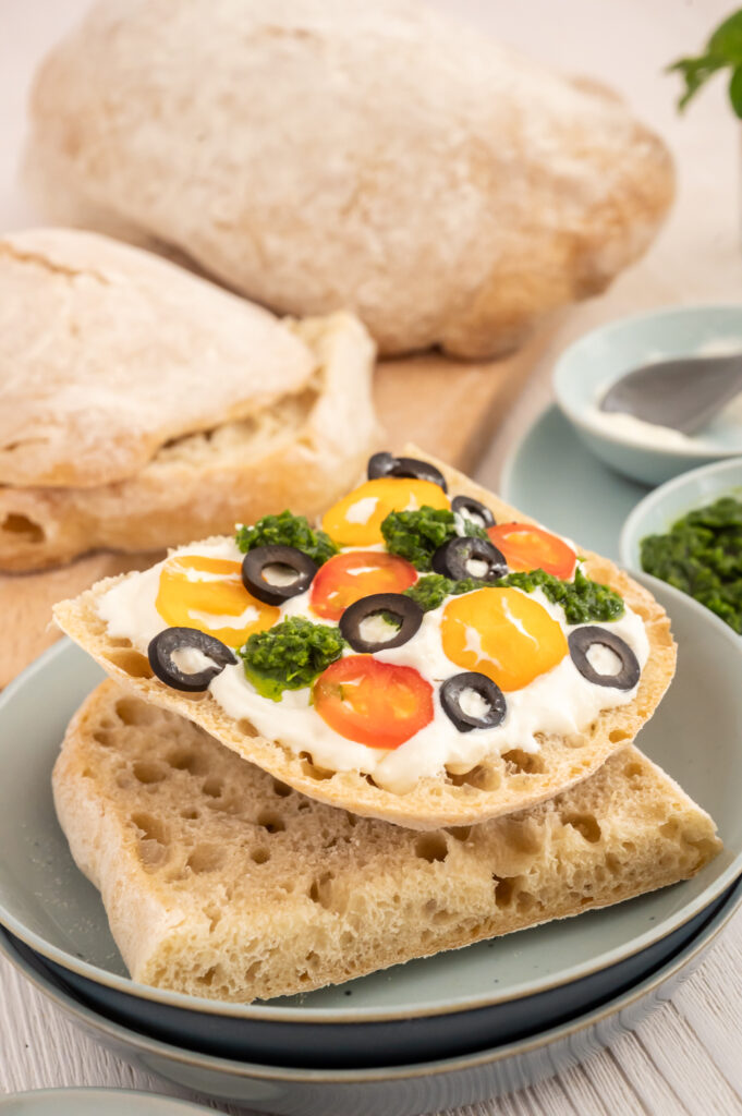 Genießen wie in Italien- Schnelles Dinkel-Ciabatta selbst backen und mit Ricotta, Tomaten und Oliven belegen.